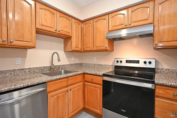 a kitchen with granite countertop cabinets stainless steel appliances and a sink