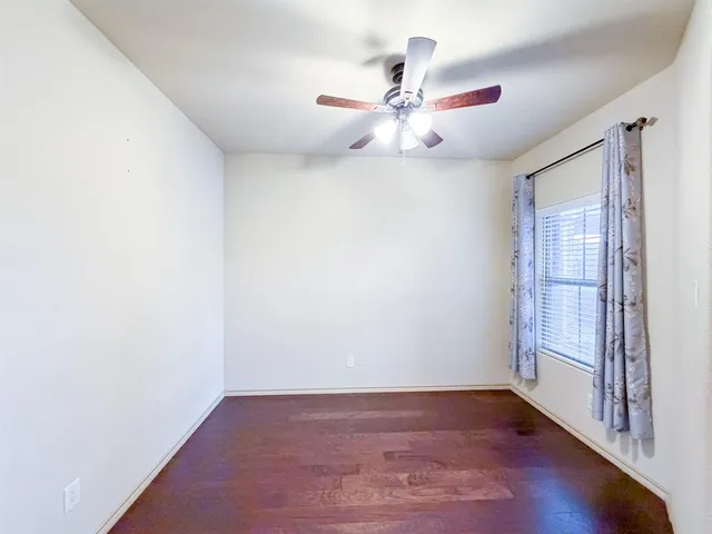 an empty room with wooden floor fan and windows