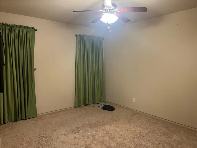 an empty room with a windows and a fan