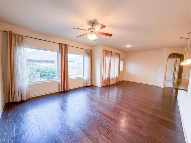 a view of an empty room with window and wooden floor