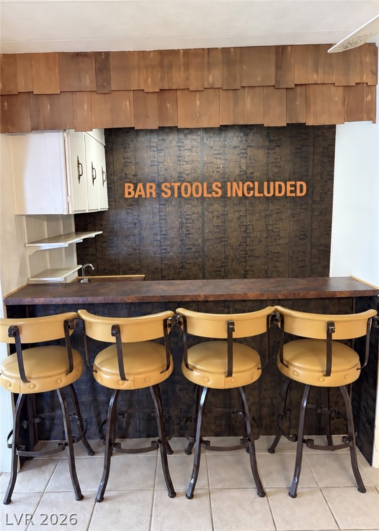 4556 Royal Ridge Way Las Vegas, NV 89103 - Photo 12 of 49 Tiled flooring extends along a custom built-in bar area complete with storage shelving.