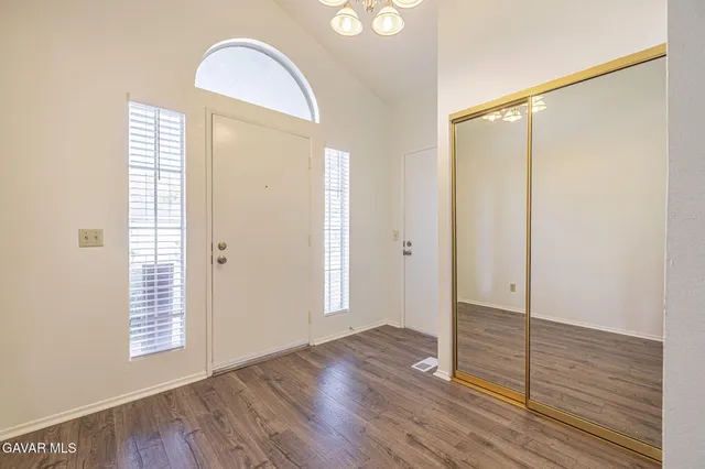 an empty room with wooden floor mirror and windows