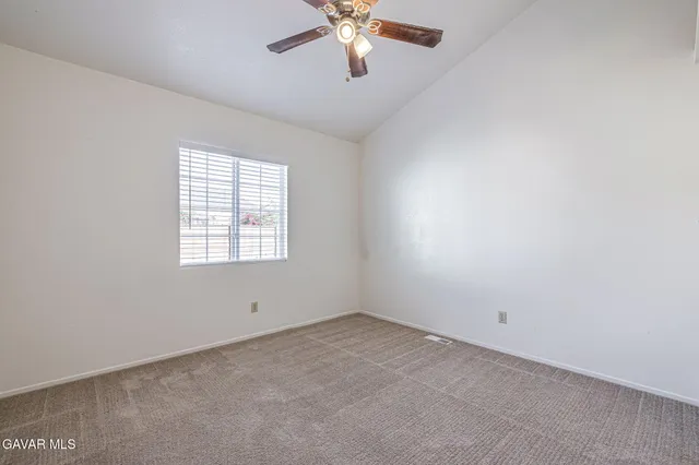 an empty room with chandelier fan and windows