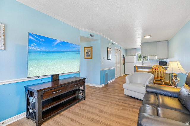 888 600 West, Unit 40 Provo, UT 84604 - Photo 5 of 19 Open-concept living area featuring wood-finish flooring, light blue wall paint with white trim, and a kitchen area with white cabinetry and a built-in countertop