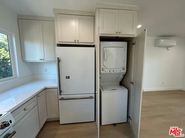 an empty room with wooden floor and kitchen view