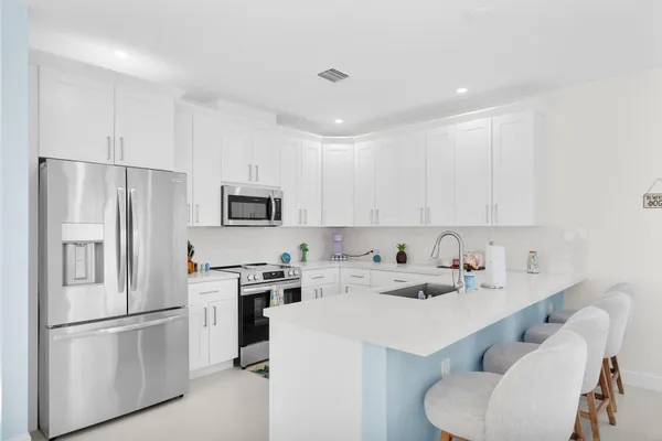 a kitchen with a sink a refrigerator and white cabinets