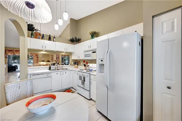 a white kitchen with stainless steel appliances granite countertop a sink a stove a refrigerator and cabinets