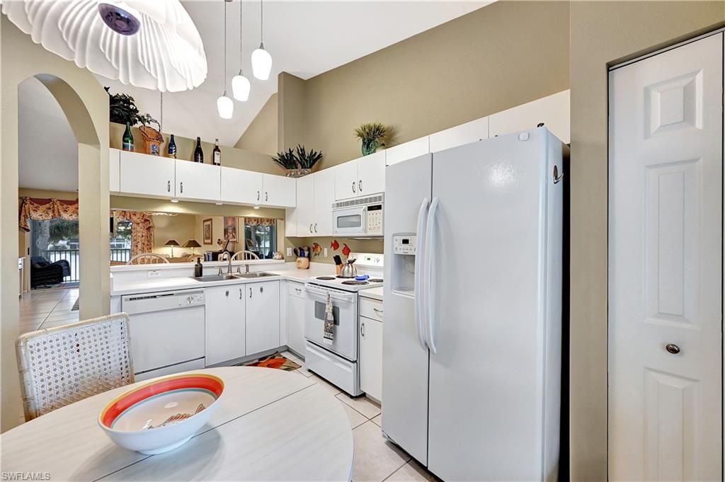 6496 Huntington Lakes Circle, Unit 201 Naples, FL 34119 - Photo 14 of 24 a white kitchen with stainless steel appliances granite countertop a sink a stove a refrigerator and cabinets