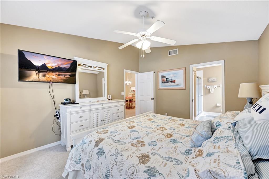 6496 Huntington Lakes Circle, Unit 201 Naples, FL 34119 - Photo 17 of 24 a bedroom with a large bed and a chandelier