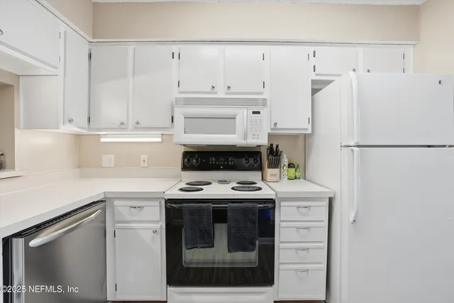a kitchen with white cabinets and white appliances