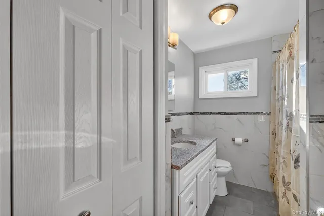 a bathroom with a granite countertop sink a toilet and shower