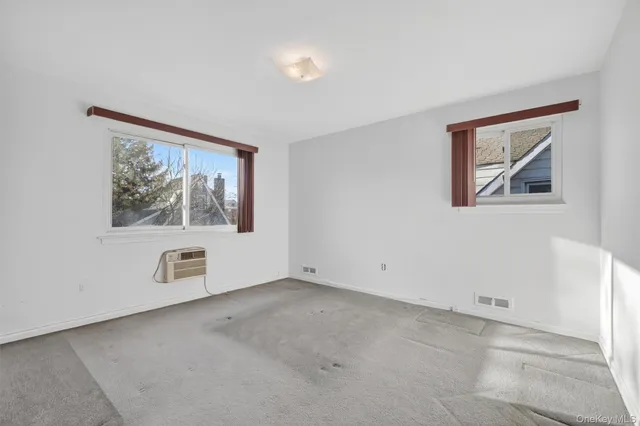 an empty room with windows and refrigerator