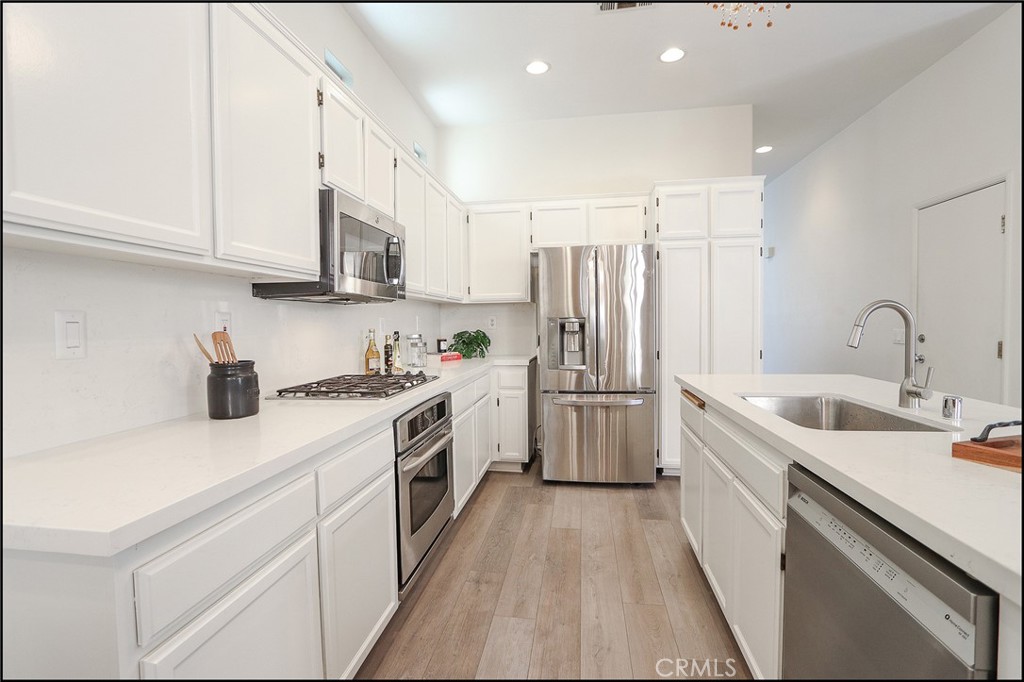3 Delfin Aliso Viejo, CA 92656 - Photo 6 of 23 a kitchen with a sink a refrigerator and white cabinets