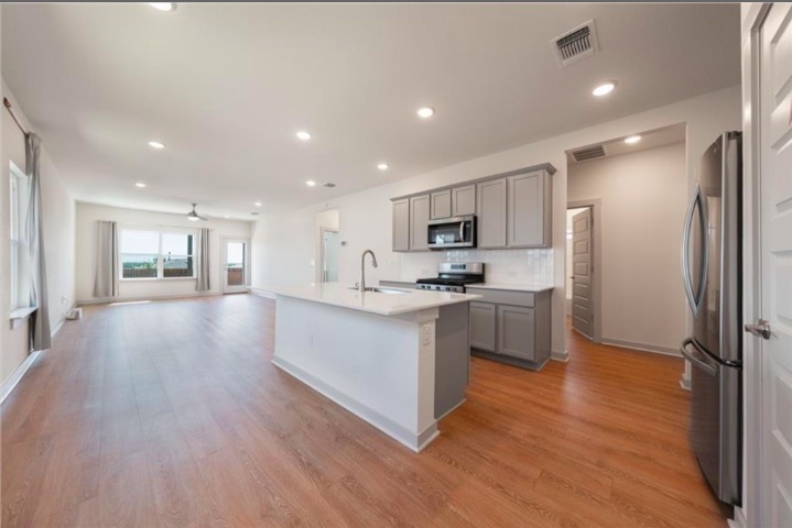10805 Meris Lane Austin, TX 78754 - Photo 6 of 28 A streamlined kitchen island anchors this inviting open-concept living space with rich hardwood flooring.
