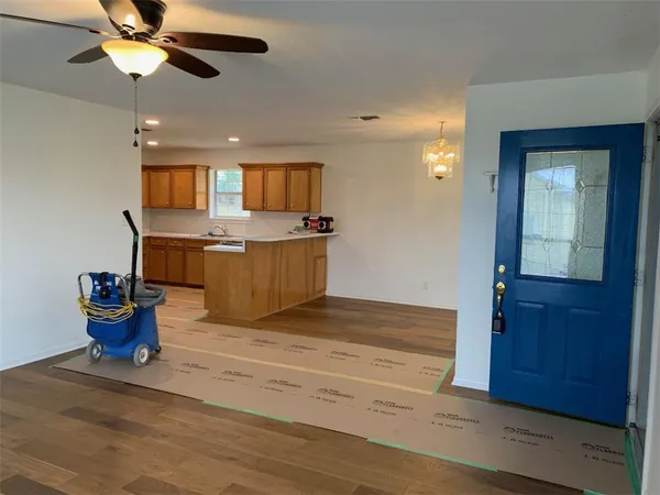 a view of living room with stainless steel appliances wooden floor dining table and chair