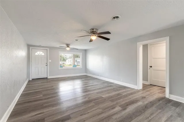 a view of an empty room with window and wooden floor