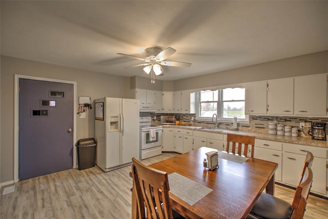 6155 Camp Warren Road Decatur, IL 62521 - Photo 7 of 18 a kitchen with stainless steel appliances granite countertop a refrigerator a stove a sink a dining table and chairs with wooden floor