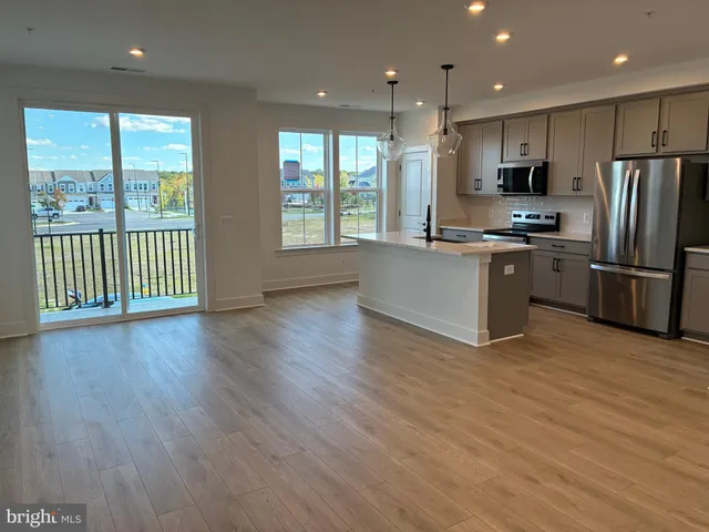 a kitchen with stainless steel appliances granite countertop a refrigerator a sink dishwasher a stove and a microwave oven on the wooden floor