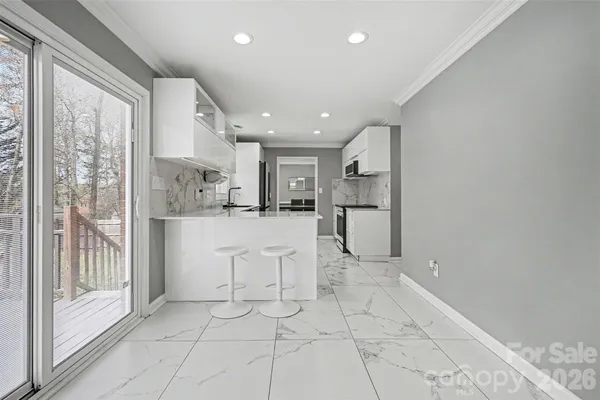 a open kitchen with white cabinets and refrigerator