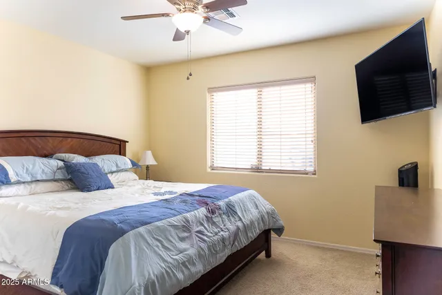 a bedroom with a bed a flat screen tv and a chandelier