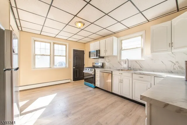 a kitchen with granite countertop white cabinets white appliances a sink and a large window