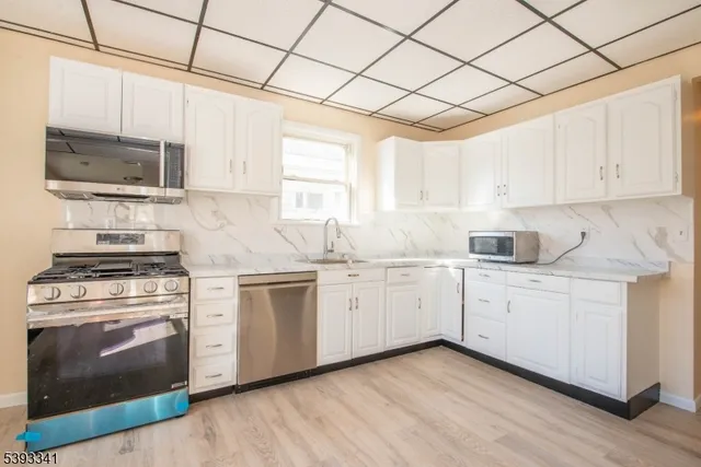 a kitchen with cabinets stainless steel appliances and wooden floor