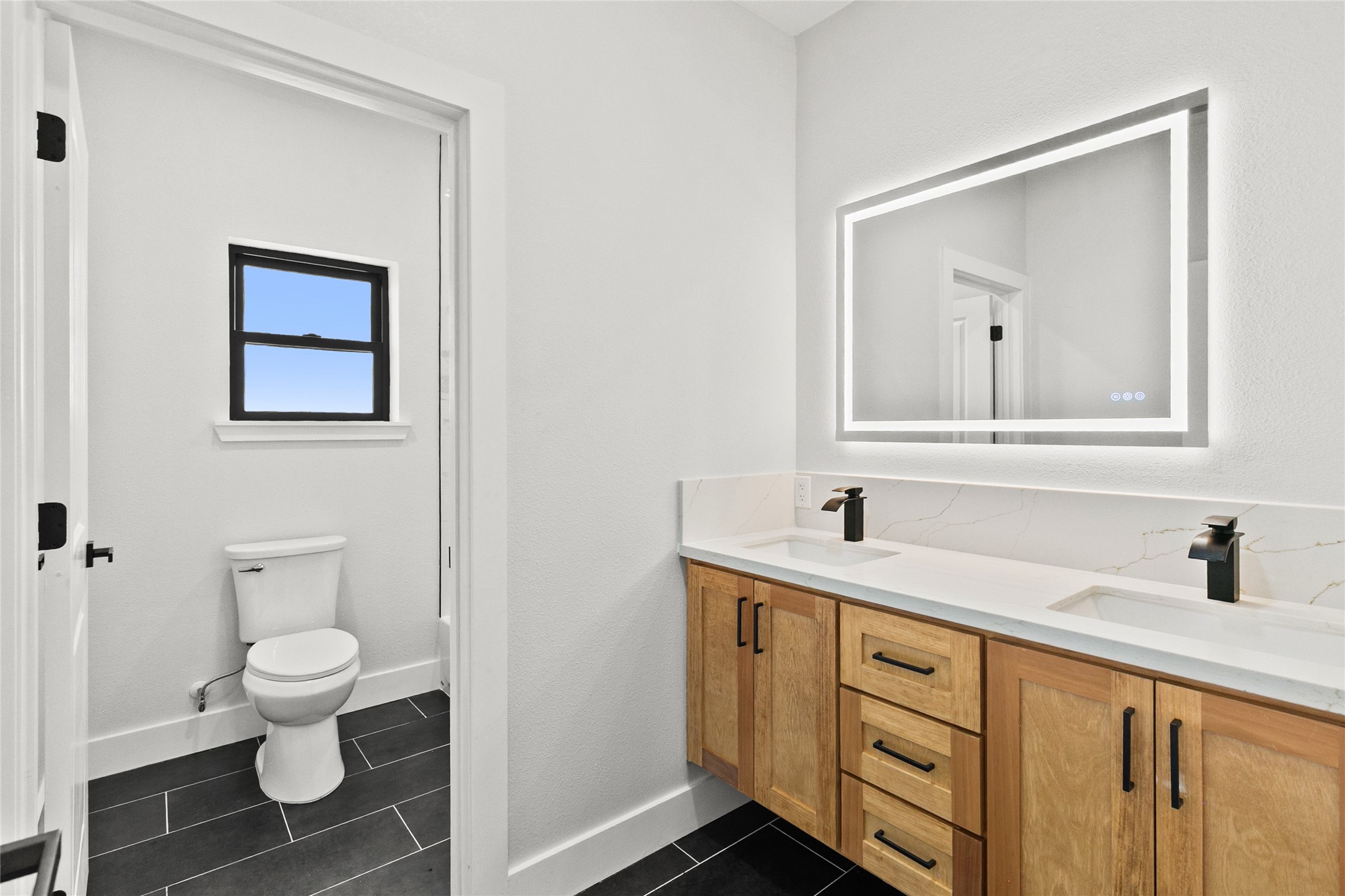 619 Chuckwagon Trail Angleton, TX 77515 - Photo 28 of 37 Thoughtfully designed guest bathroom featuring a floating double vanity, illuminated mirror, and a separate tub/shower and water closet area for added comfort and convenience.