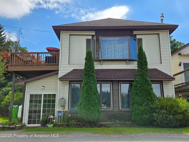 a front view of a house with a yard and potted plants