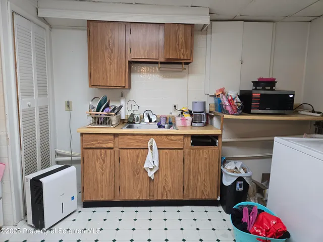 a utility room with sink dryer and cabinets