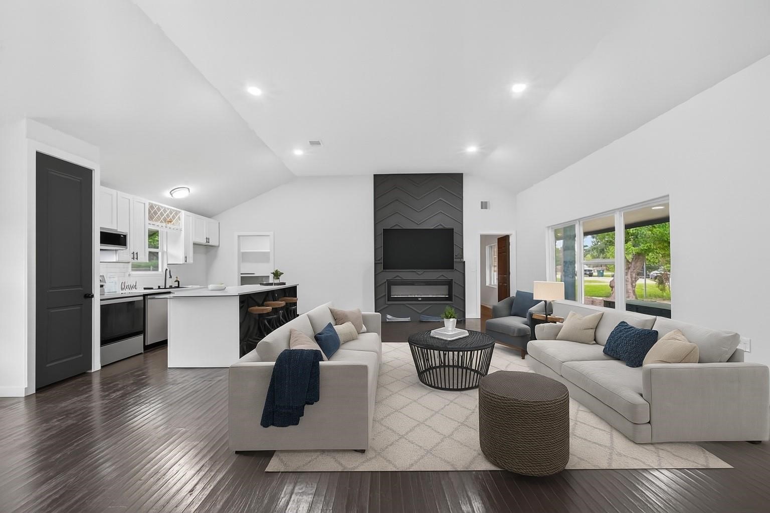 a living room with stainless steel appliances furniture and a flat screen tv