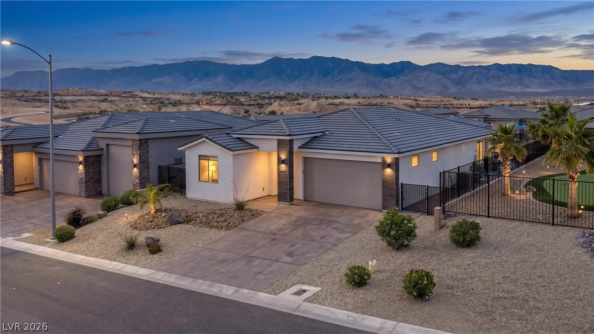 1436 Manassas Ridge Mesquite, NV 89027 - Photo 2 of 77 A desert oasis home, offering sweeping mountain vistas under the twilight sky.