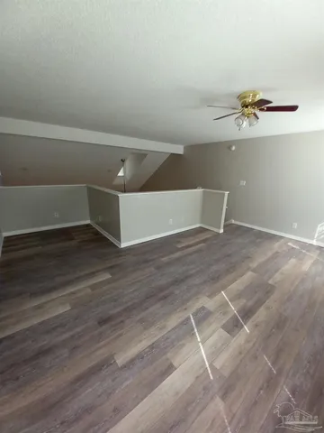 an empty room with wooden floor and a ceiling fan