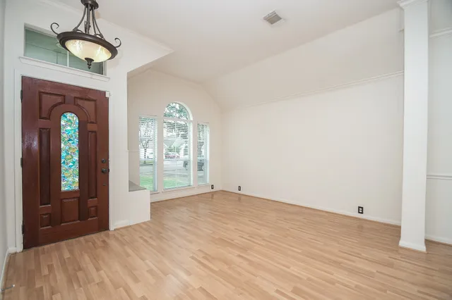 a view of empty room with wooden floor and fan
