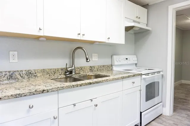 a kitchen with granite countertop a sink and white cabinets