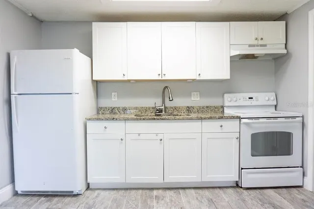 a kitchen with granite countertop white cabinets and white appliances
