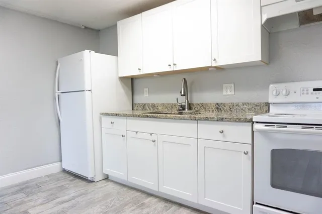 a kitchen with granite countertop white cabinets and white appliances