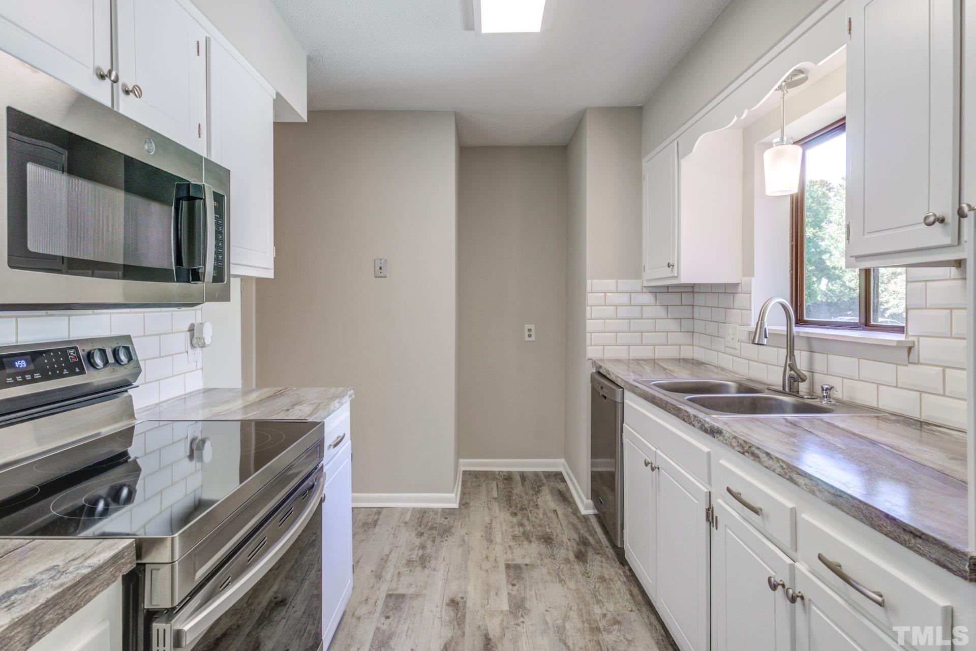 5062 Flint Ridge Place, Unit 5062 Raleigh, NC 27609 - Photo 3 of 23 a kitchen with stainless steel appliances granite countertop a sink stove and microwave