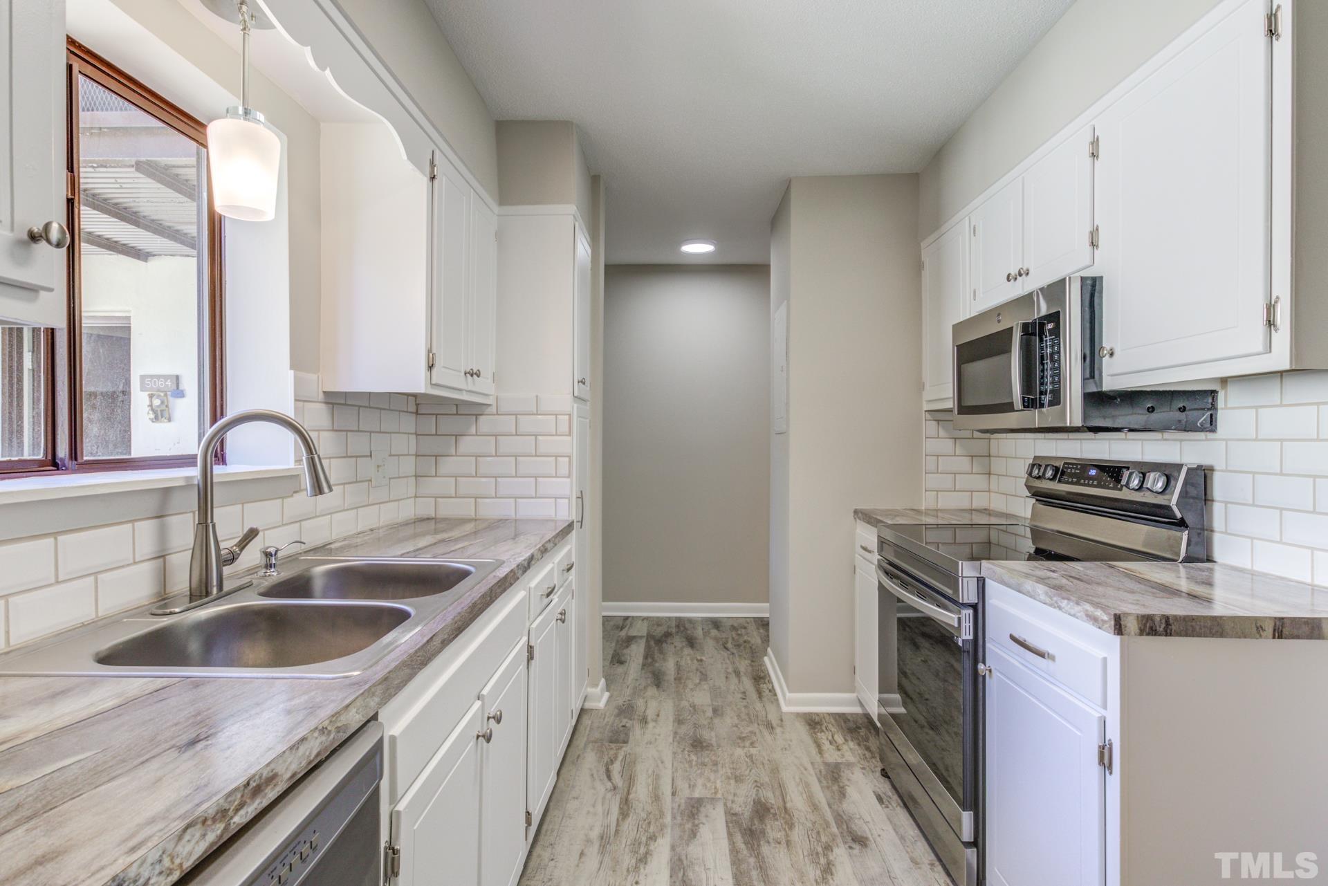 5062 Flint Ridge Place, Unit 5062 Raleigh, NC 27609 - Photo 6 of 23 a kitchen with stainless steel appliances granite countertop a sink stove and refrigerator