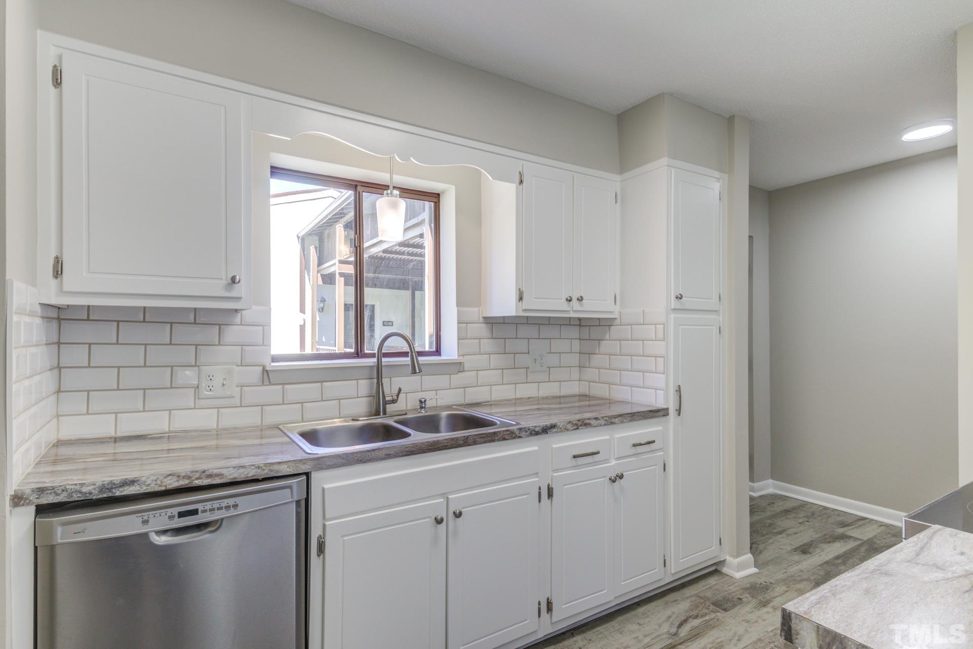 5062 Flint Ridge Place, Unit 5062 Raleigh, NC 27609 - Photo 7 of 23 a kitchen with stainless steel appliances granite countertop white cabinets and window