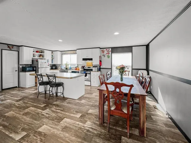 a dining area with stainless steel appliances kitchen island granite countertop a dining table chairs and granite counter tops