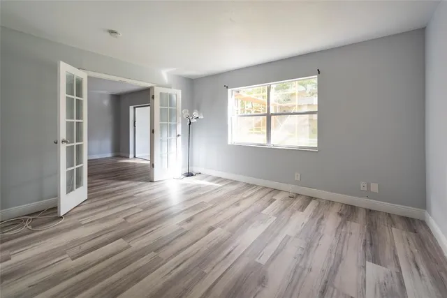 an empty room with wooden floor and windows