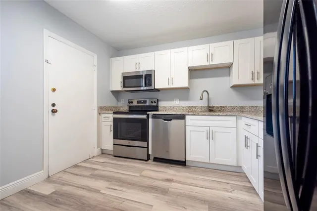 a kitchen with white cabinets and appliances