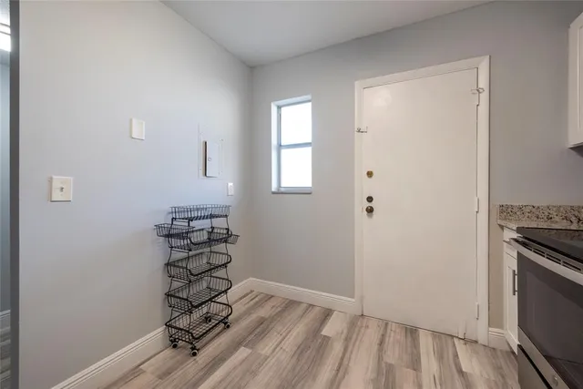 an empty room with wooden floor cabinet and windows