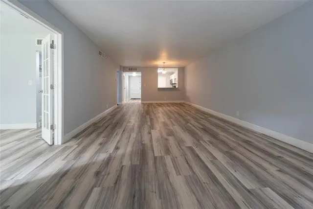 a view of empty room with window and wooden floor