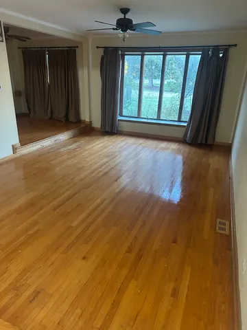a view of an empty room with a window and wooden floor
