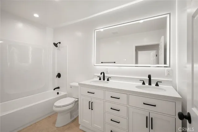 a bathroom with a toilet a sink a bathtub and a mirror