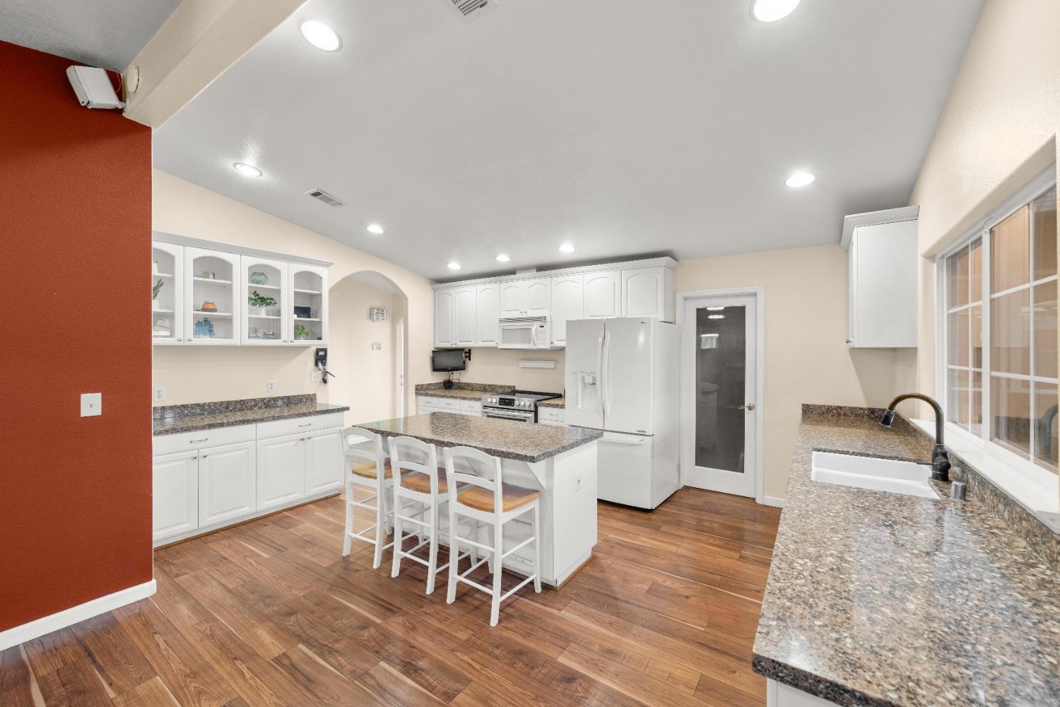 5001 Boyd Drive Carmichael, CA 95608 - Photo 6 of 49 a kitchen with stainless steel appliances granite countertop a stove top oven a sink a refrigerator and white cabinets with wooden floor