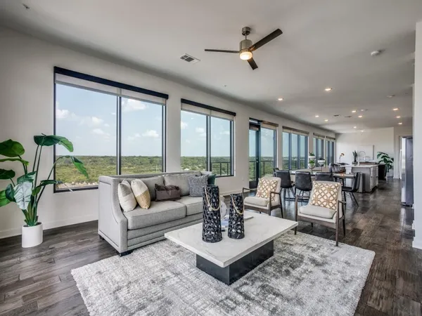 a living room with furniture large windows and wooden floor