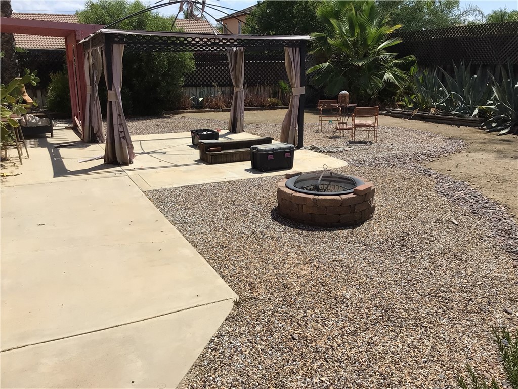 763 Anthirium Avenue Perris, CA 92571 - Photo 20 of 20 a view of a backyard with table and chairs potted plants and large tree