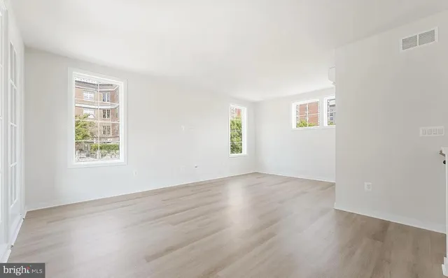 an empty room with wooden floor and windows